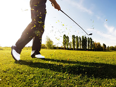 Ein Golfer schwingt einen Schläger, während Grasstücke durch die Luft fliegen.